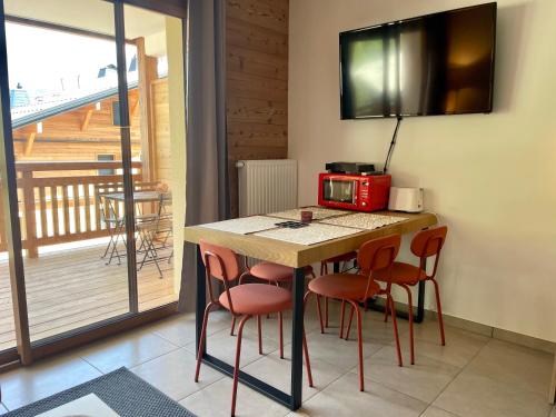 une cuisine avec une table avec des chaises et un micro-ondes dans l'établissement Appartement charmant au pied des pistes, à Saint-Jean-dʼAulps
