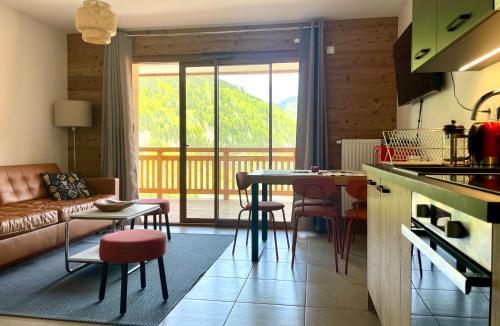 une cuisine et un salon avec une table et des chaises dans l'établissement Appartement charmant au pied des pistes, à Saint-Jean-dʼAulps
