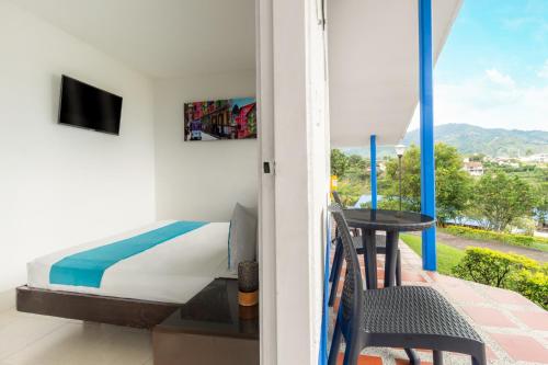a bedroom with a bed and a balcony with a table at Hotel Villa Mónaco in Pereira