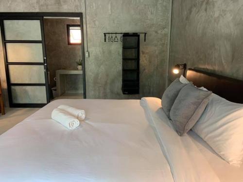 a large white bed with two rolled towels on it at Khao Yai Cottage in Mu Si