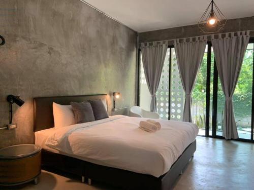 a bedroom with a large bed and a large window at Khao Yai Cottage in Mu Si