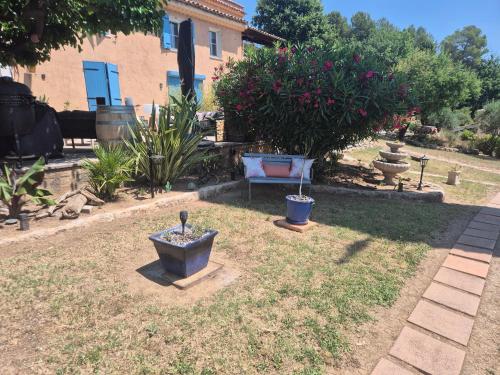 a yard with a bench and plants in front of a house at Gites Colline De Sollies in Salernes