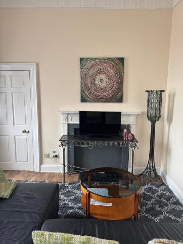 a living room with a table and a fireplace at 52, Charlotte Street Apartments in Glasgow