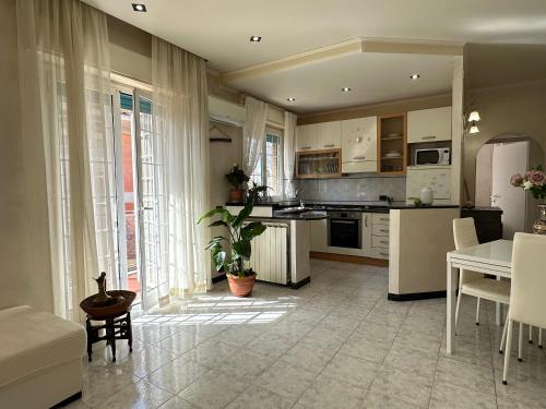 a kitchen with white cabinets and a table and a refrigerator at Casa Liliana in Ladispoli