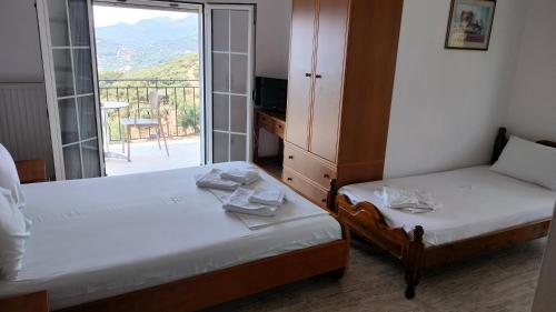 two beds in a room with a view of a balcony at Studios Evgenia Parga in Parga