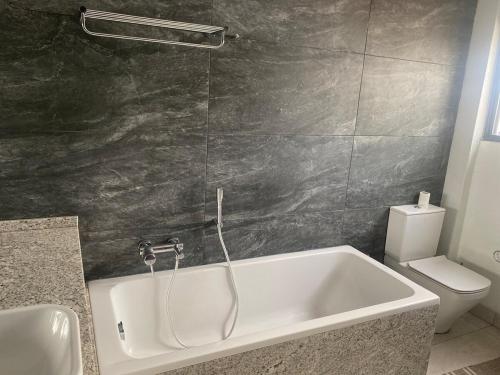a bathroom with a bath tub and a toilet at PLSA Lovely Three Bedroom Home in Accra