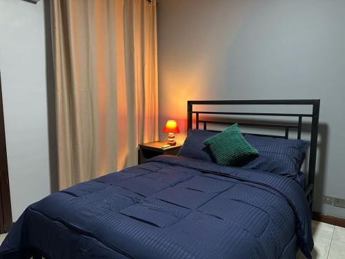 a bedroom with a blue bed with a lamp on a table at PLSA Lovely Three Bedroom Home in Accra