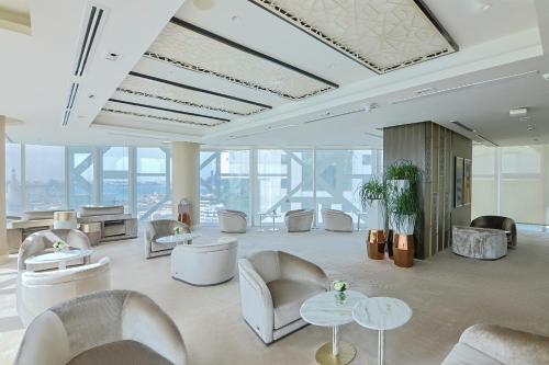 a lobby with white chairs and tables and windows at Shaza Doha in Doha