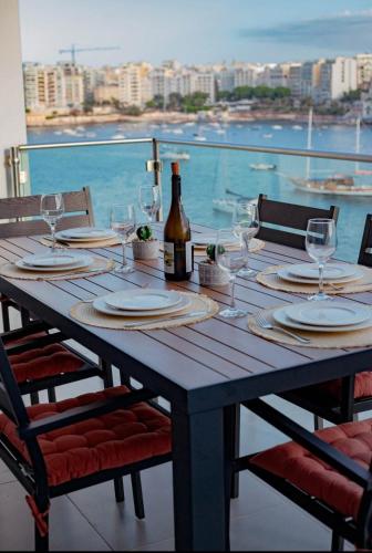 a wooden table with glasses and a bottle of wine at Brilliance of the sea apt in St Julian's