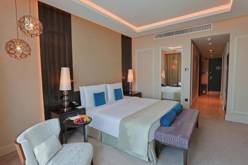 a bedroom with a large white bed and a chair at Shaza Doha in Doha