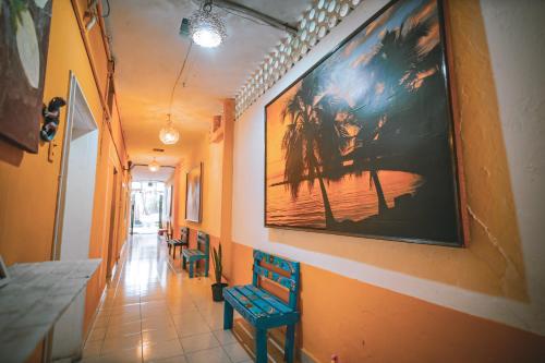 un couloir avec des chaises et un grand tableau sur le mur dans l'établissement Hotel Posada Aurora, à Mérida