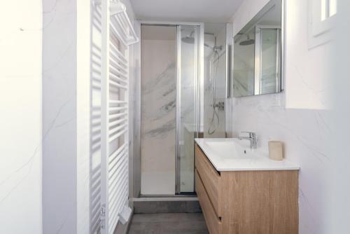 a white bathroom with a sink and a shower at L'essentiel, calme et climatisé - Accès autonome in La Ferté-Gaucher
