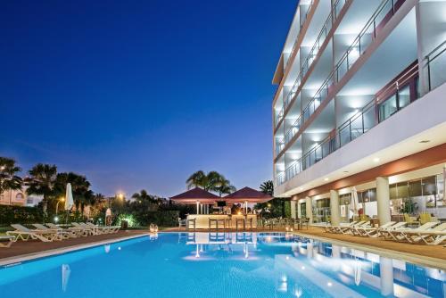 a swimming pool in front of a building at Areias Village Beach Suite Hotel in Albufeira