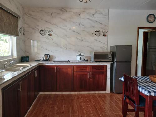 a kitchen with wooden cabinets and a sink and a refrigerator at Praslin Orchid Villa in Grand Anse