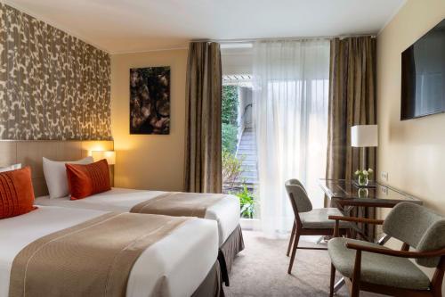 a hotel room with two beds and a desk at Jardins Eiffel in Paris