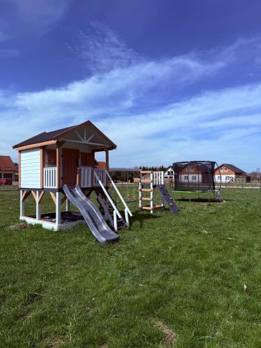 a playground with a small house and slides in a field at Makówka in Mysłakowice