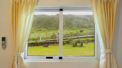 a window with a view of a mountain at 伊那部海景民宿 Inapu Ocean View B&B in Lanyu