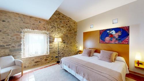 a bedroom with a large bed and a stone wall at Arcs De Monells - Adults Only in Monells