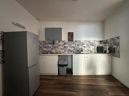  La cuisine est équipée de placards blancs et d'un réfrigérateur. dans l'établissement T2 Spacieux et lumineux, au Puy-en-Velay