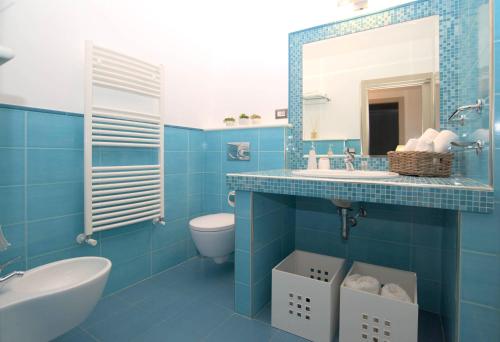 uma casa de banho azul com um lavatório e um WC em Taonasi Mazzarò Apartments em Taormina