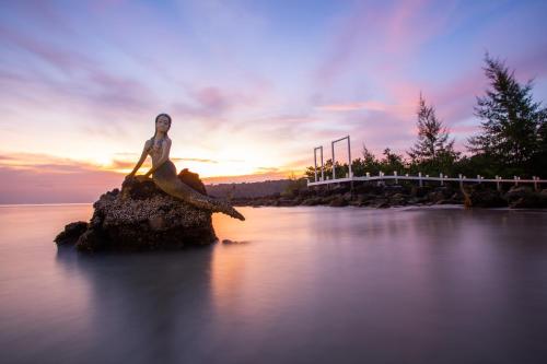 a statue of a woman sitting on a rock in the water at Mafiya Resort in Koh Rong Island