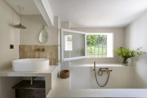une salle de bain blanche avec un lavabo et une fenêtre dans l'établissement La Maison Méditerranéenne, à Roquefort-les-Pins
