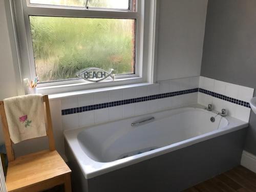 Una bañera blanca en un baño con ventana. en The Seagulls Perch, en Weymouth