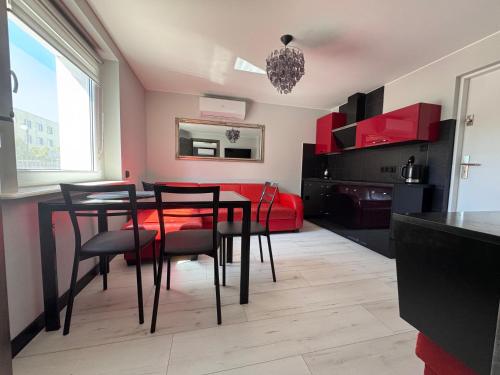a dining room with a table and chairs and a red couch at Migor Apartamenty in Łeba