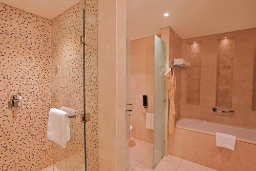 a bathroom with a shower and a toilet and a tub at Shaza Doha in Doha