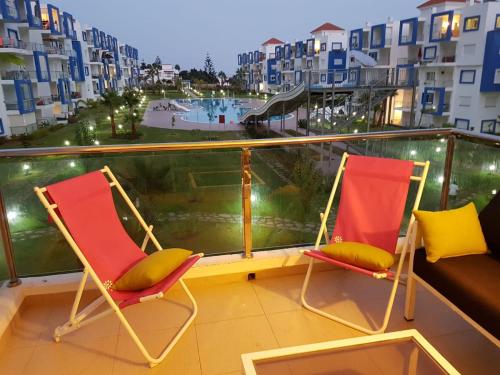 two chairs on a balcony with a view of a pool at Grand appartement avec piscines in Cabo Negro