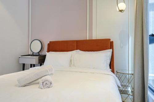 a bedroom with a bed with white sheets and a mirror at Paxtonz Exsim By NexxField in Petaling Jaya