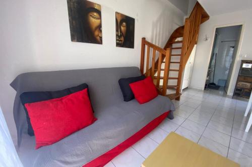 - un canapé gris avec deux oreillers rouges dans le salon dans l'établissement Marine Wave, à Aresquies