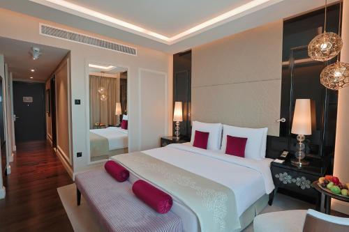 a bedroom with a large white bed with red pillows at Shaza Doha in Doha