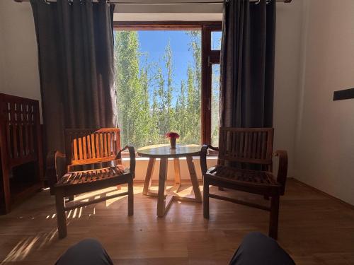 a room with two chairs and a table and a window at BARCHA Guest house in Leh