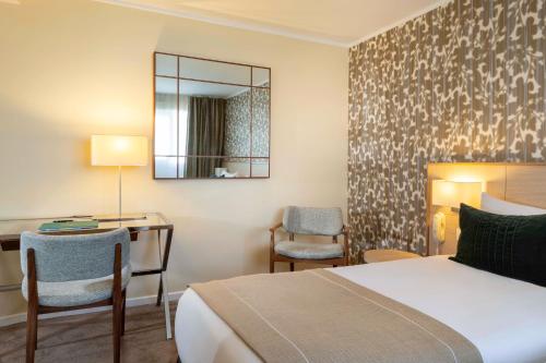a hotel room with a bed and a desk and a mirror at Jardins Eiffel in Paris