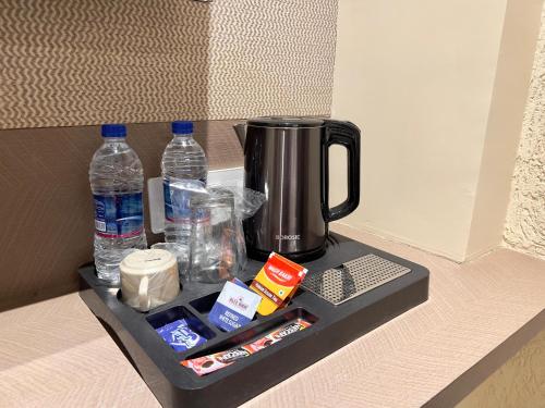 a counter with a coffee maker and bottles of water at Hotel Grand Pragati in Surat