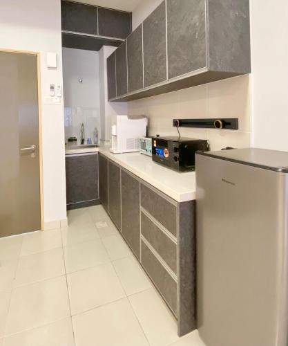 a kitchen with gray cabinets and a refrigerator at Studio with Rooftop Pool at Youth City Nilai by D'KAY HOMES, near USIM KLIA in Nilai