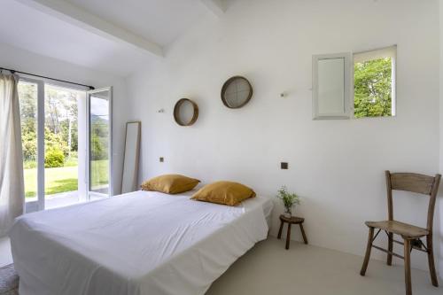 une chambre blanche avec un lit et une chaise dans l'établissement La Maison Méditerranéenne, à Roquefort-les-Pins