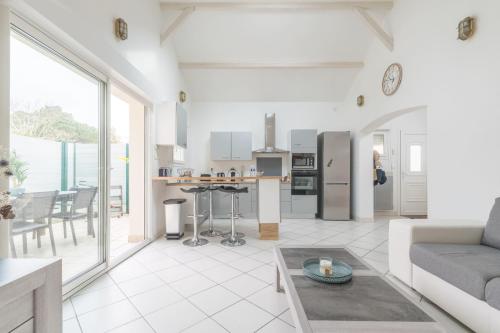 Il comprend un salon blanc avec un canapé et une cuisine. dans l'établissement MARGUERITE - Wifi - Parking, à Pornichet