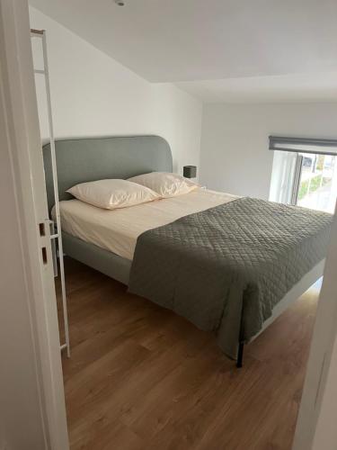 Ce lit se trouve dans une chambre blanche dotée de parquet. dans l'établissement Appartement hyper centre-ville, à Vaison-la-Romaine