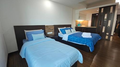 two beds in a hotel room with blue sheets at KITA Studio - Kota Bharu City Point in Kota Bharu
