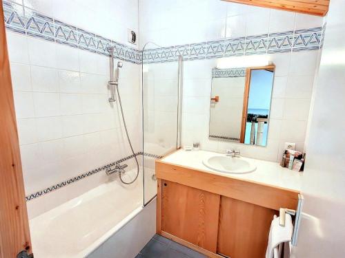 une salle de bain avec un lavabo, une baignoire et un miroir dans l'établissement T3 au pied des pistes avec parking et WiFi - FR-1-598-128, aux Gets