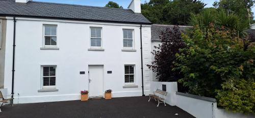 a white house with a bench in front of it at Ryan's Cottage in Rostrevor