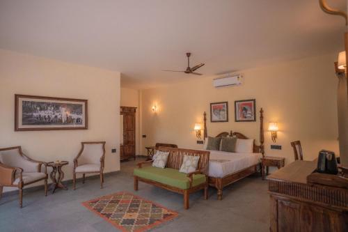 a bedroom with a bed and chairs in a room at Aloof Jungle Lodge in Ghānerao