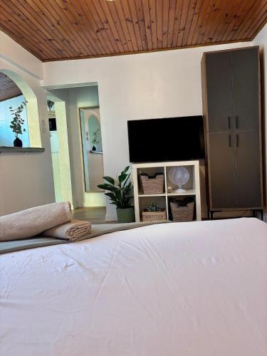 une chambre avec un lit blanc et une télévision dans l'établissement Studio Bougainvillier, à La Seyne-sur-Mer