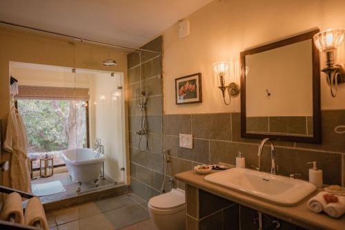 a bathroom with a sink and a toilet and a mirror at Aloof Jungle Lodge in Ghānerao