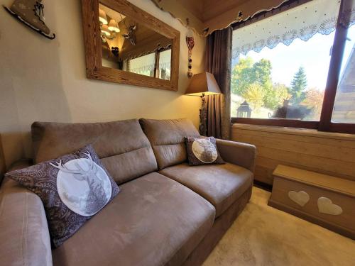 - un salon avec un canapé brun et un miroir dans l'établissement Studio cocooning rénové avec parking et mezzanine - FR-1-598-113, aux Gets