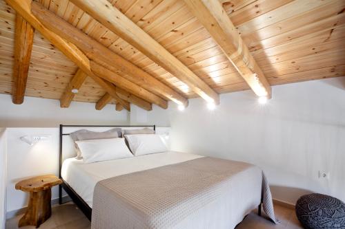 a bedroom with a white bed and wooden ceilings at Olive Dryopis Apartments in Kithnos
