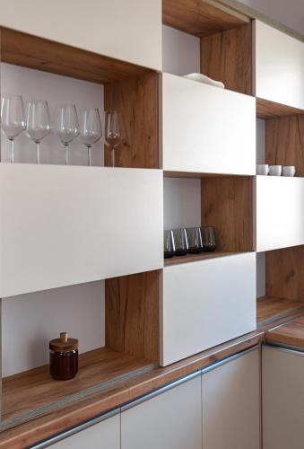 a kitchen with white and wooden shelves and wine glasses at Poseidon Nest - 2BR, 360 Sea View, Office, Pool in Durrës