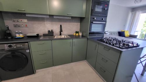 a kitchen with green cabinets and a washing machine at Hanapartment 3 bed Ayia NAPA in Ayia Napa